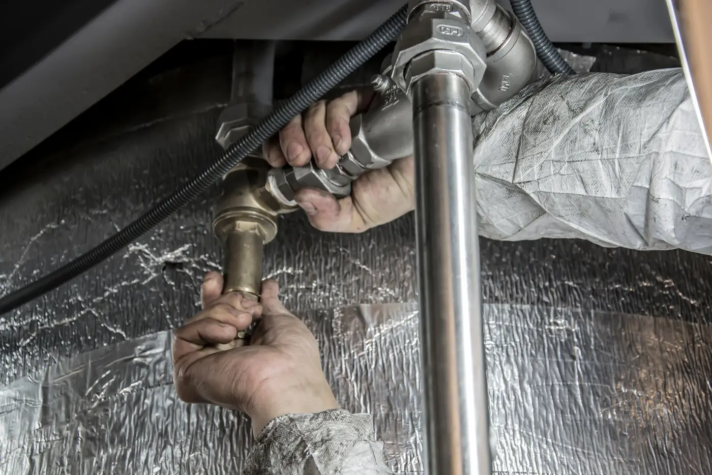 Gloved hands fitting brass pipe connections