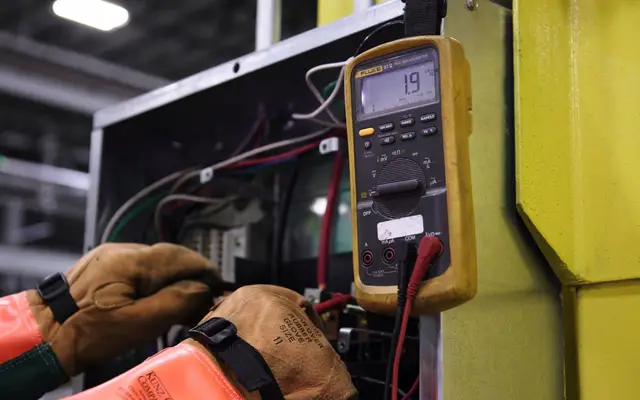 Electrician testing a home electrical panel with a multimeter