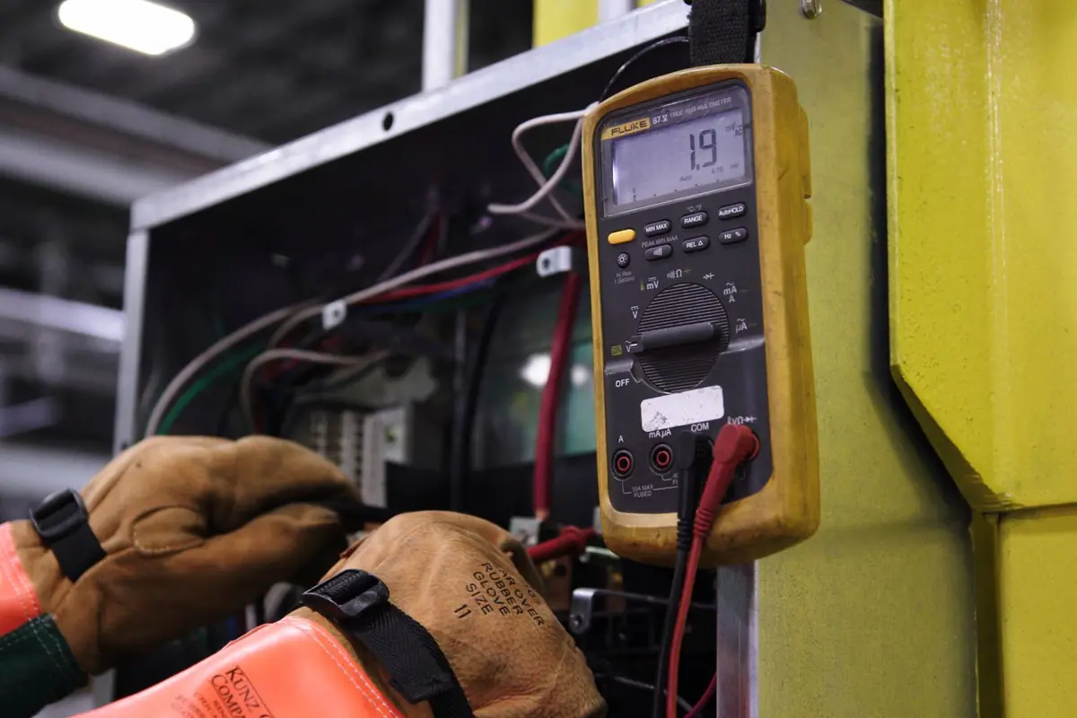 Electrician testing panel wiring with a multimeter