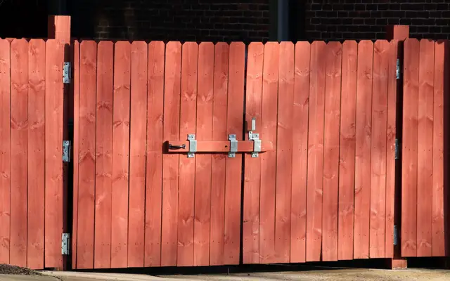 Red wooden fence with a metal gate latch