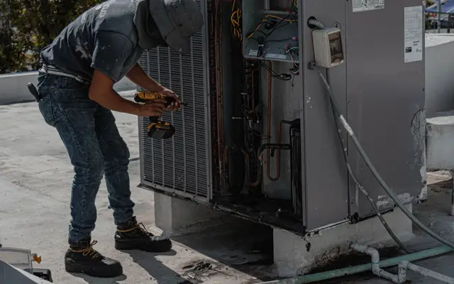 HVAC technician repairing a home's outdoor air conditioning unit