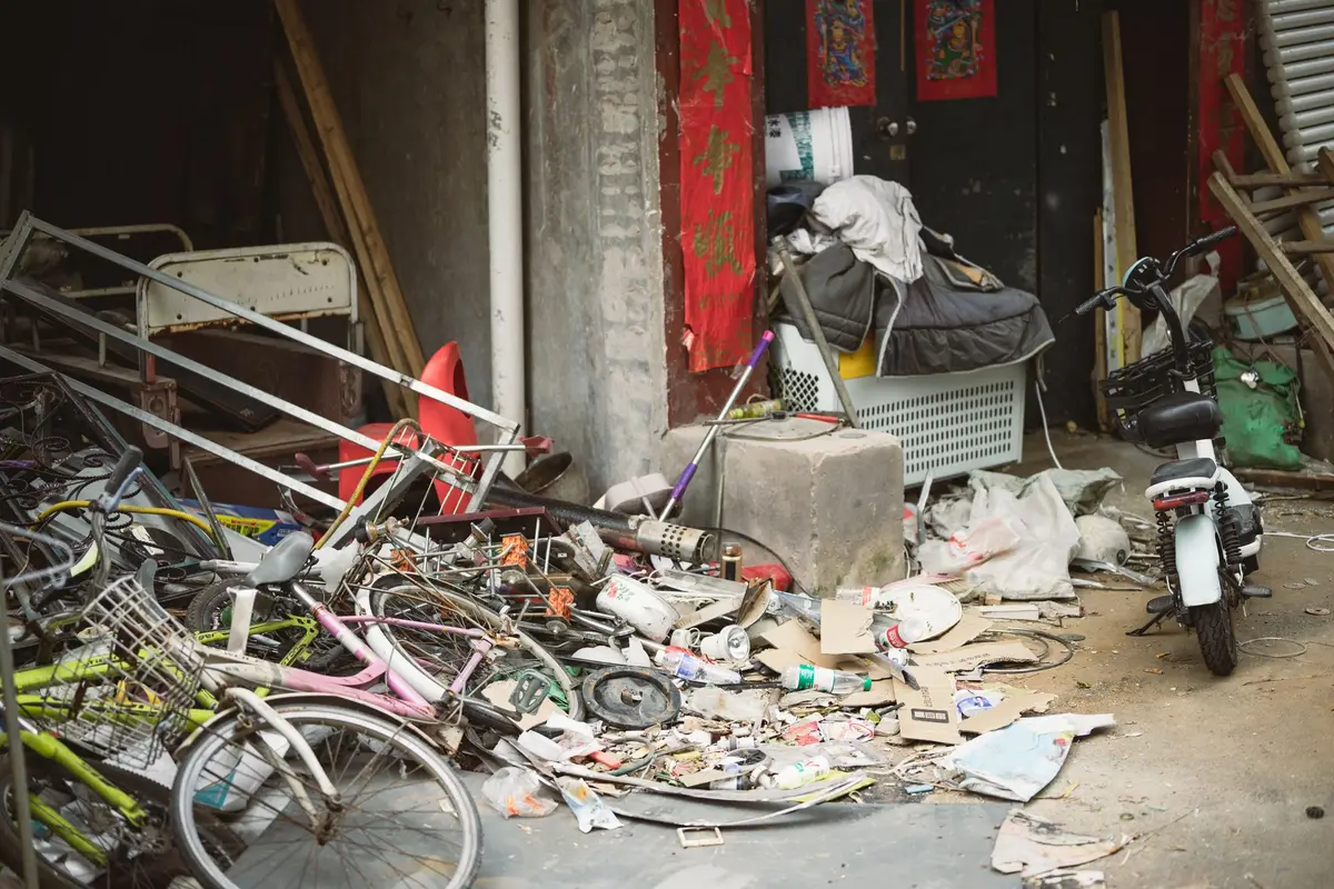 Old bicycles, scrap metal and debris piled beside a building