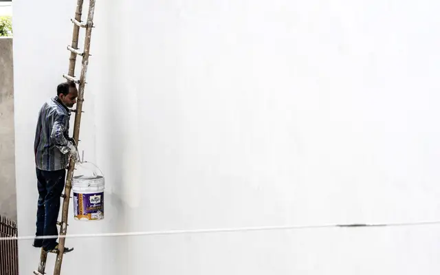 House painter on a ladder painting an exterior wall