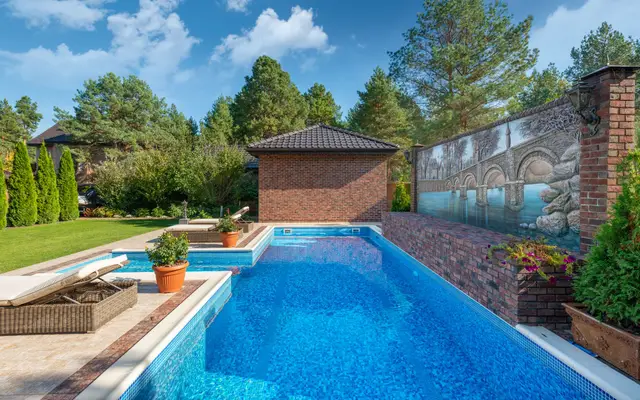 Backyard swimming pool behind a brick home