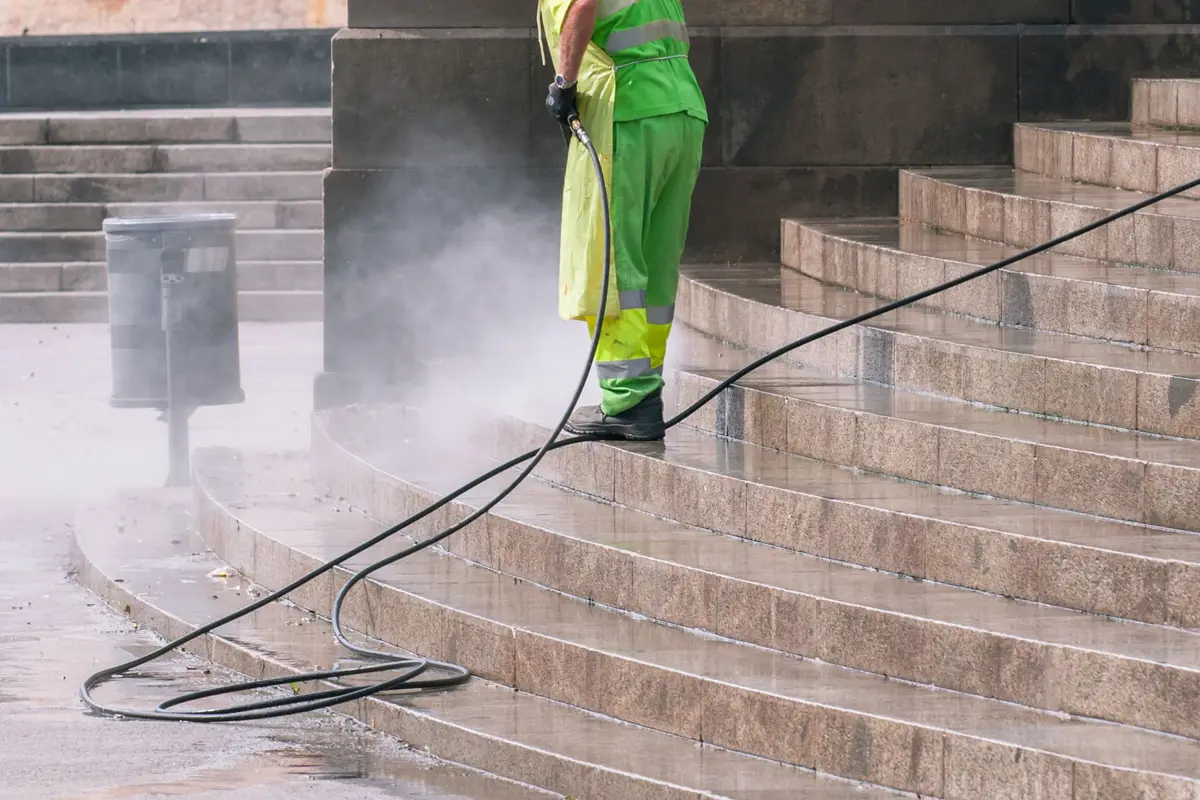 Worker pressure washing stone steps