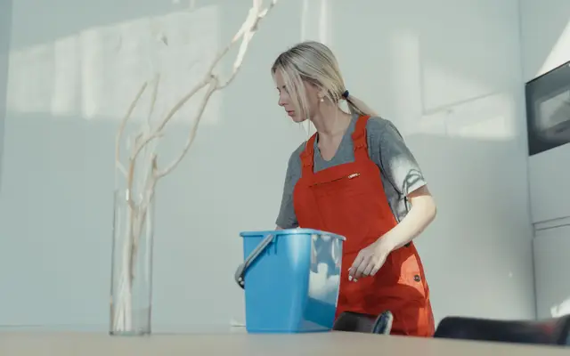 Residential house cleaner in uniform cleaning a room