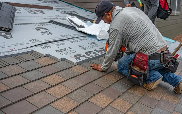 Roofer installing asphalt shingles on a residential roof